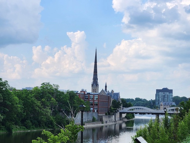 canal landscape with church steeple. A bridge stretches out across the water and blue sky over head 